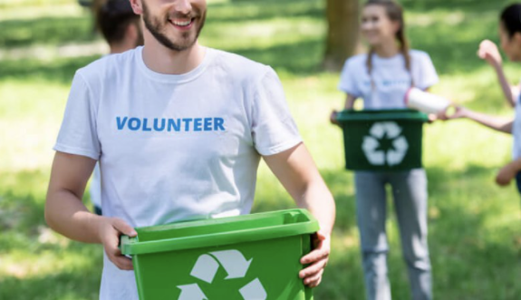 Man and woman holding recycling buckets in a grass field